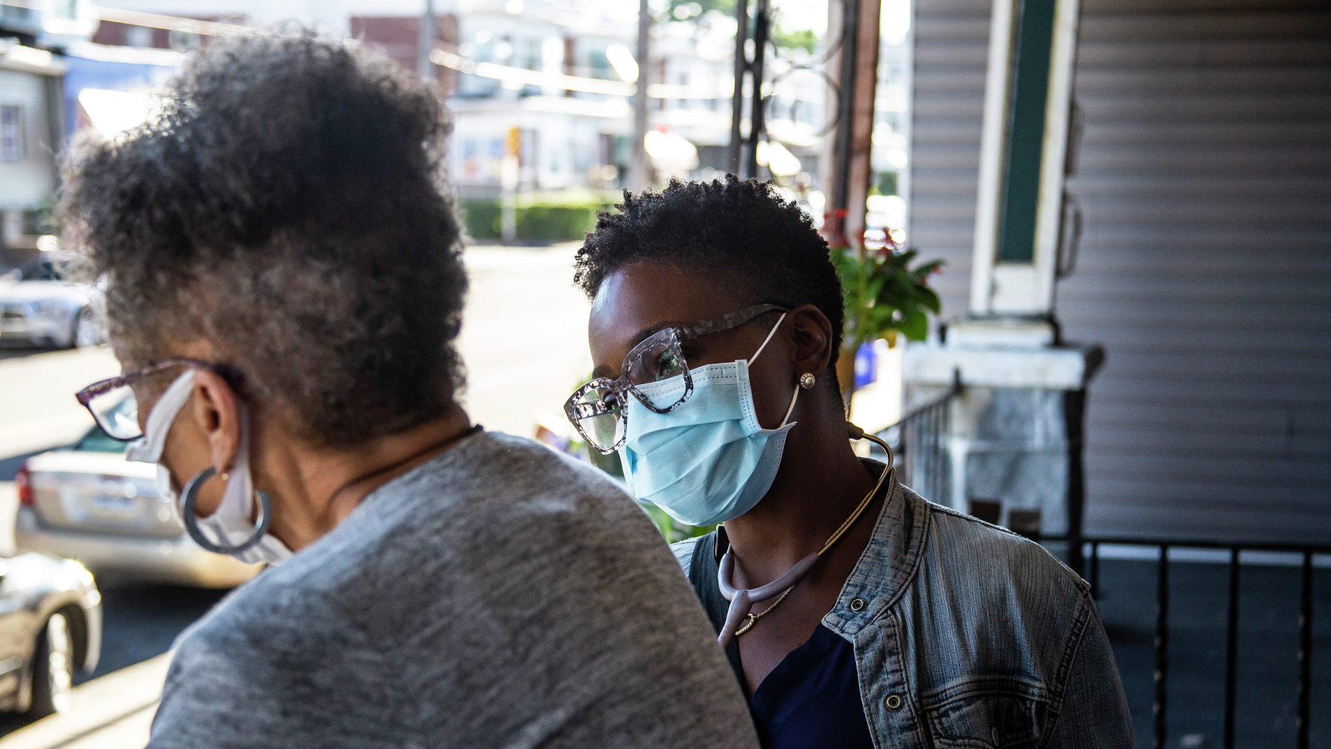 Renee Jones looks at her patient Valerie Simon while standing on a front porch in Southwest Philadelphia