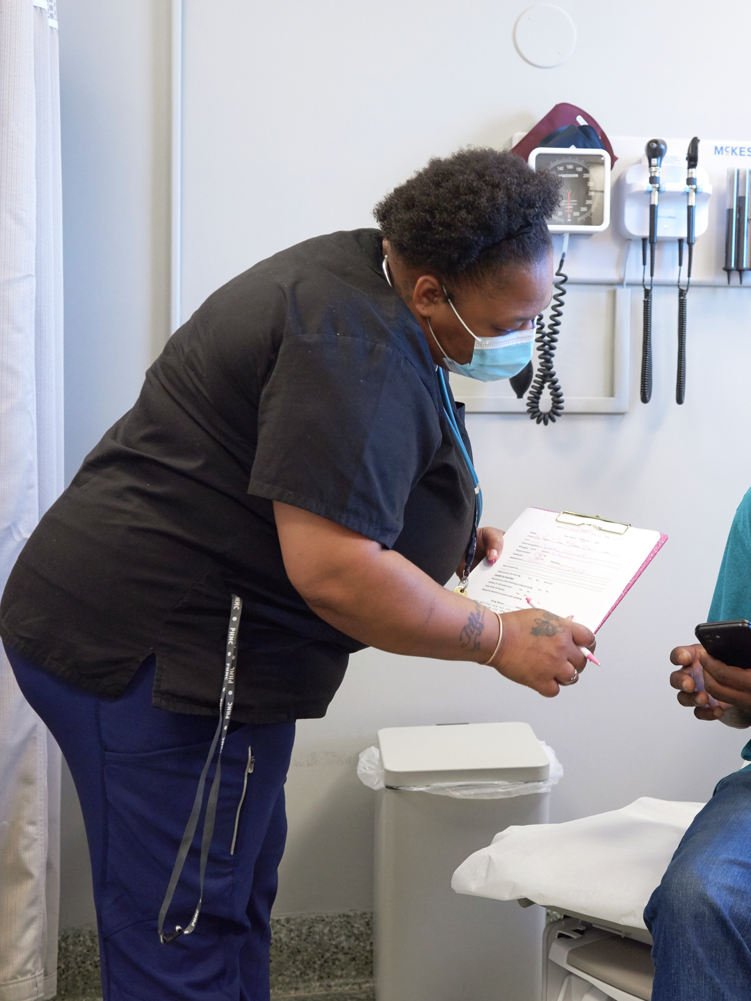 Nathaniel Williams checks information on his phone to show to medical assistant Jameria Randolph