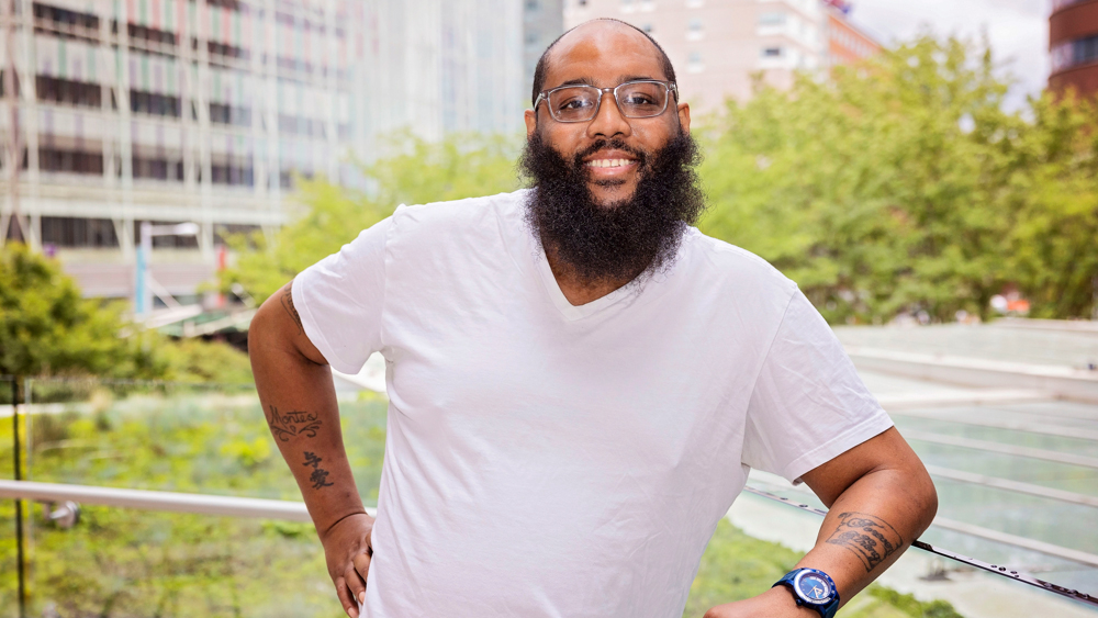 Garcia Bolton, a 40-year-old Black man with a large beard and glasses, smiles with a calm expression