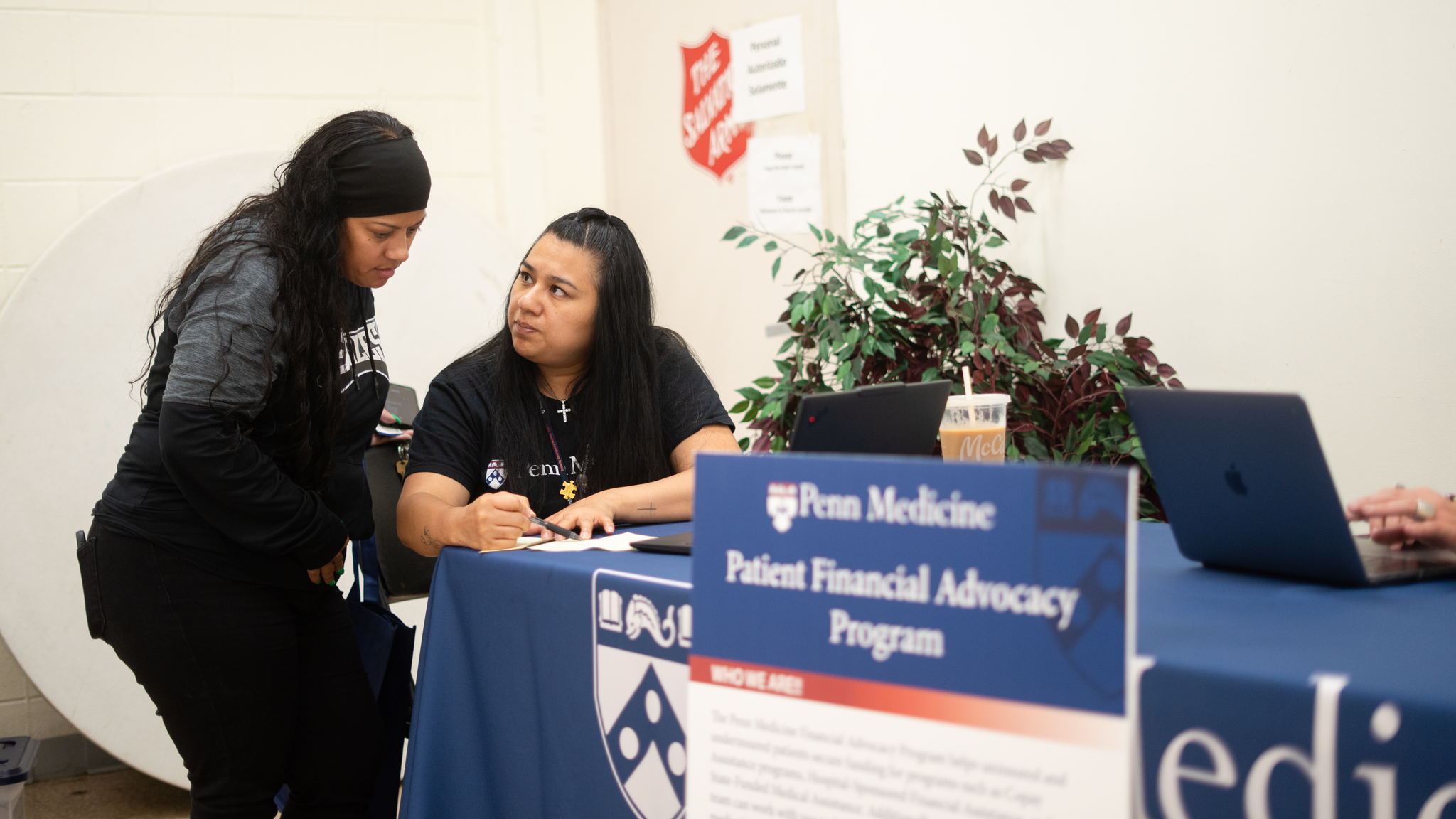 A Penn Medicine financial advocate speaks with a community member at an information table during an outreach event