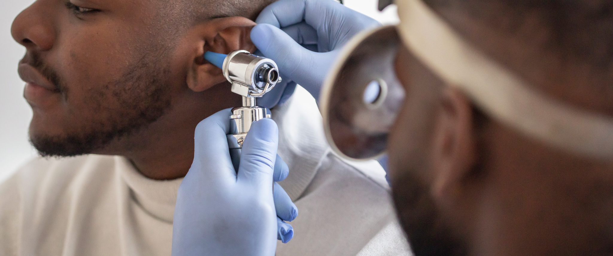 Close up of a male doctor carefully holding the ear of his patient to establish a clearer view of the inside of his ear