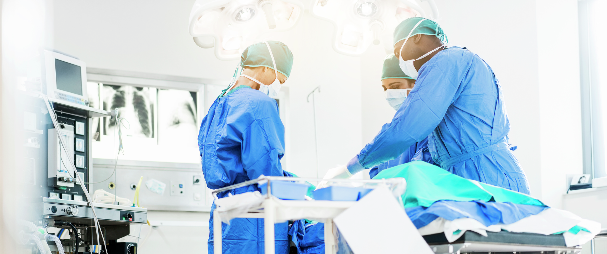 Surgeons operate below lighting equipment