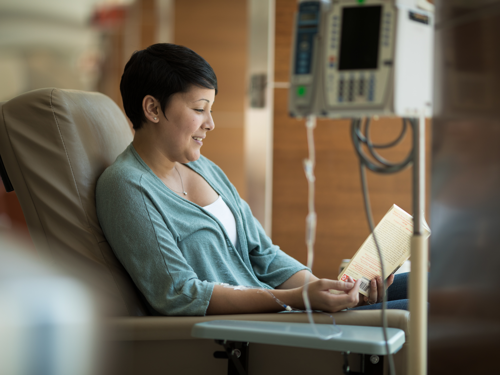 Cancer patient reading a book while receiving infusion therapy