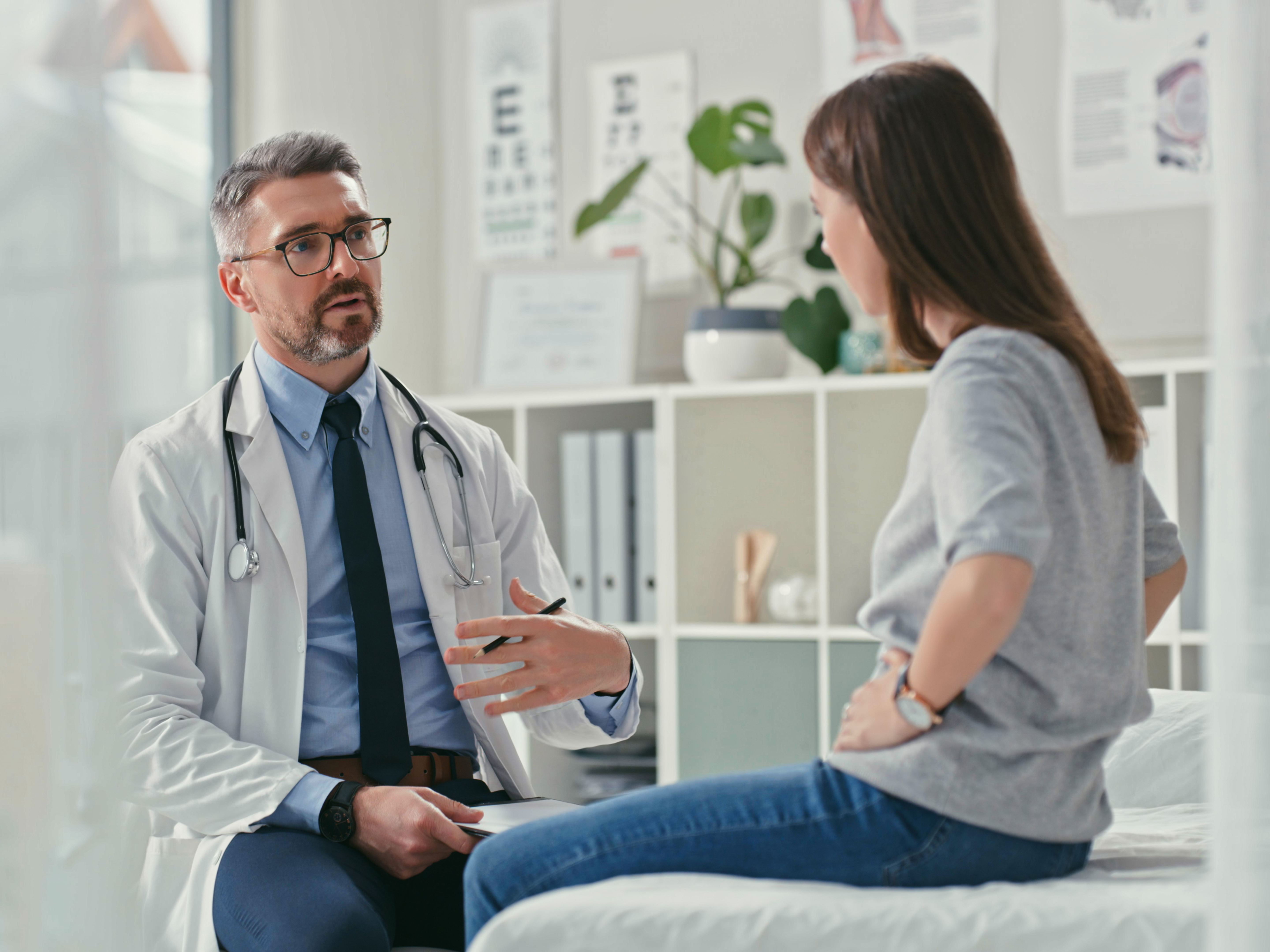 Shot of a mature doctor sitting with his patient in the clinic and asking questions during a consultation