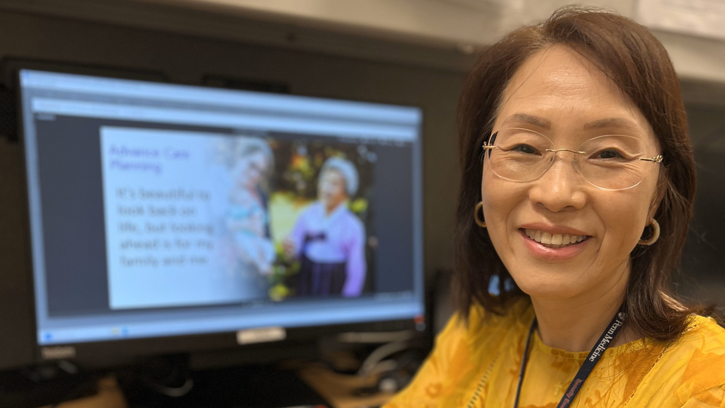 Eunice Park-Clinton sits in front of a computer monitor showing her presentation about advance care planning
