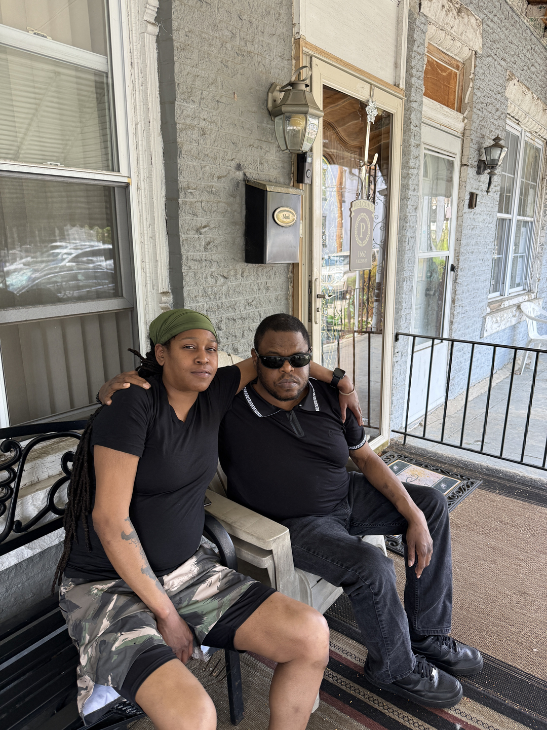 Donald Peacock and Shay Bryan are sitting in chairs on the front porch of a home in Philadelphia. They have their arms around each other. Peacock was the first patient of Penn Medicine's new Hospital at Home program