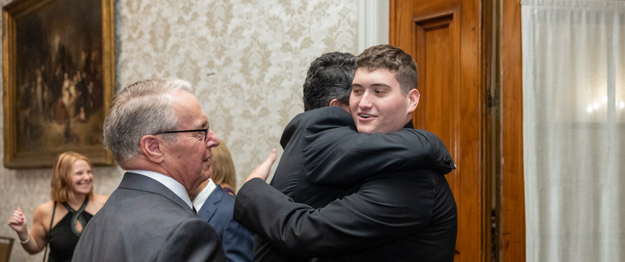 John Pryor, Jr. embraces another man as William Schwab, MD, looks on.