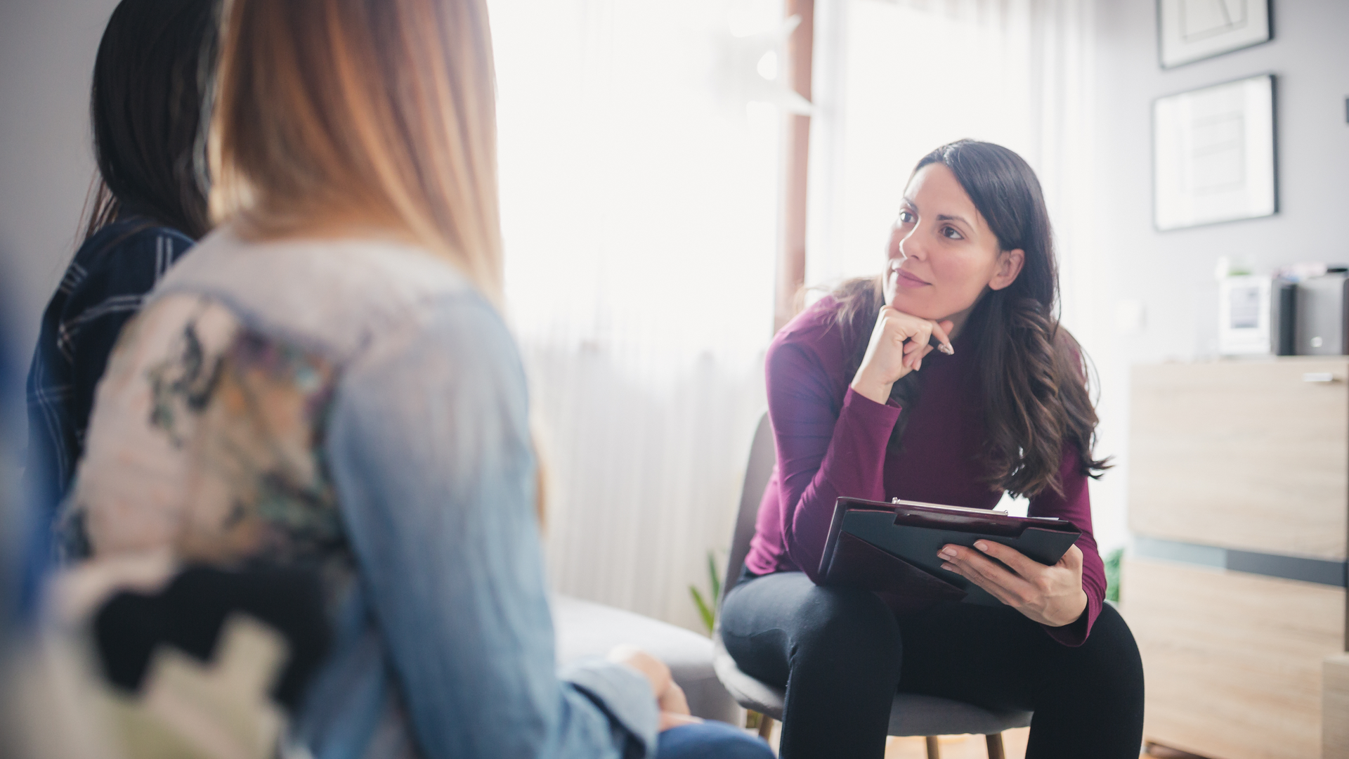 Doctor facing two women couple listening with head on hand