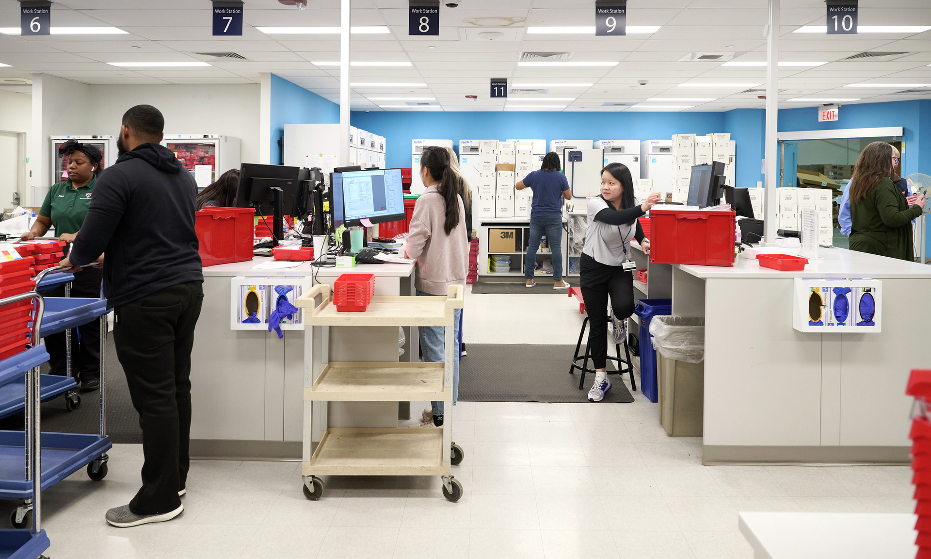 Pharmacists at Penn Medicine’s Specialty Pharmacy sort and fill prescriptions by checking information on computers and placing medications into red bins