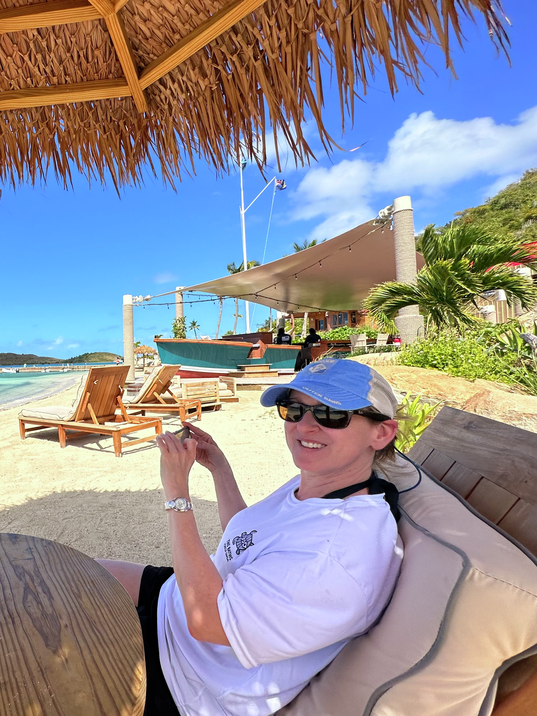 Kim Bello sitting under thatch umbrella on a tropical island beach