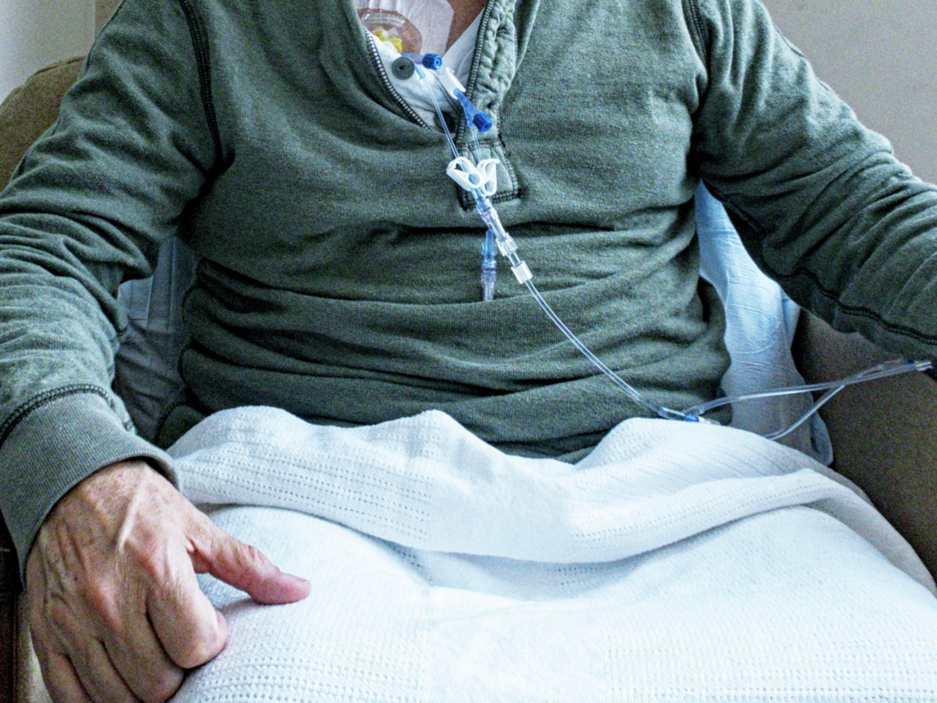 Older adult hands with blood cancer treatment in progress