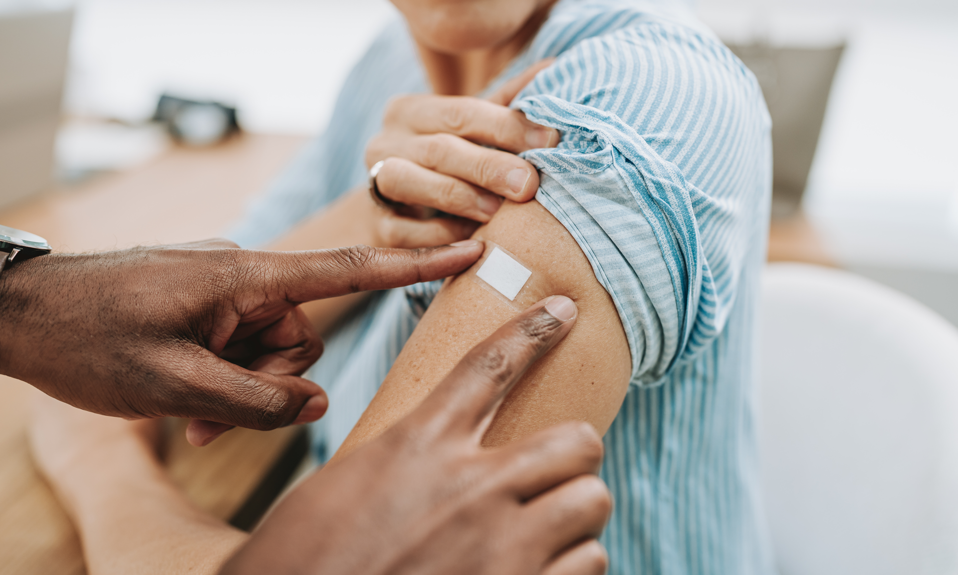 A doctor applies an adhesive bandage to older patient's arm