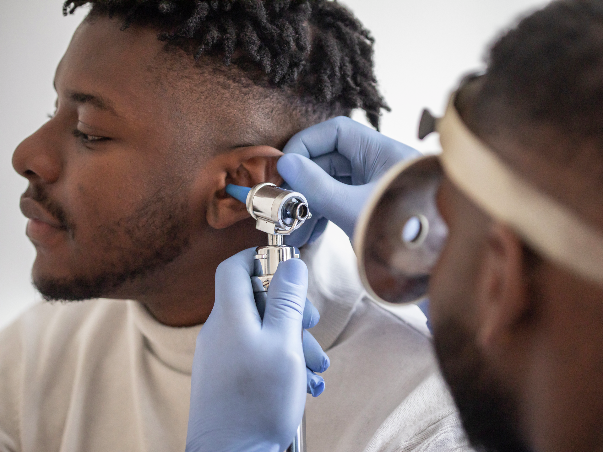 Close up of a male doctor carefully holding the ear of his patient to establish a clearer view of the inside of his ear