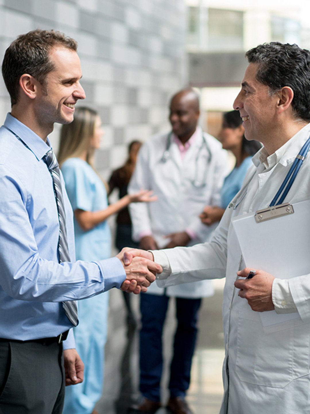 Two physicians shake hands in a hallway