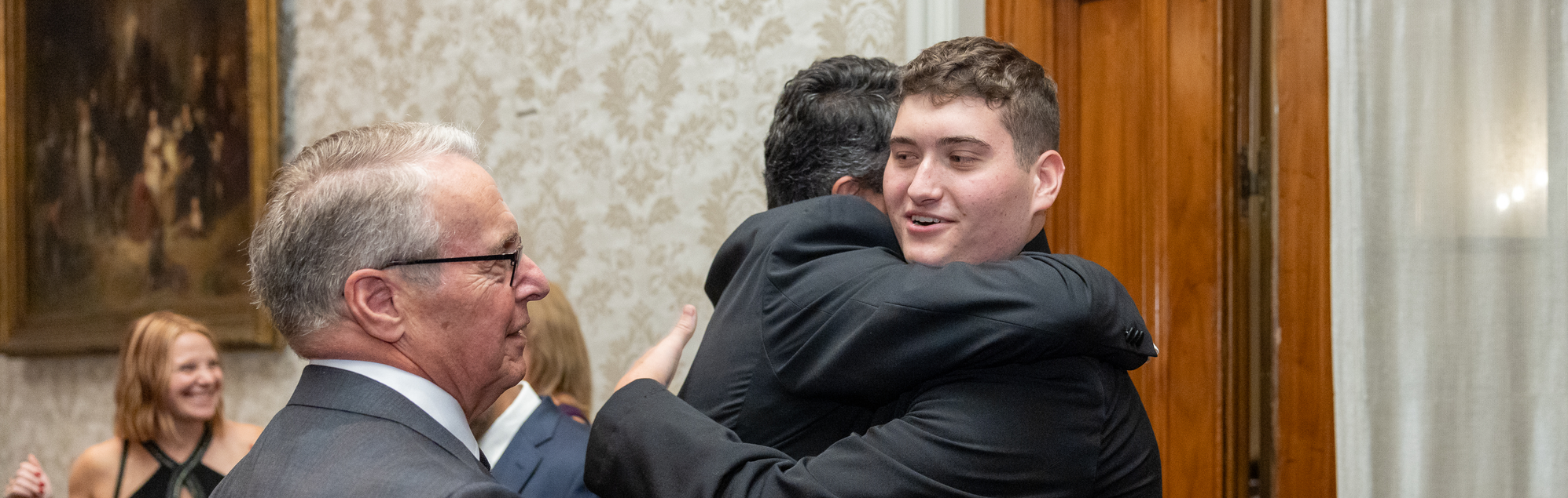 John Pryor, Jr. embraces another man as William Schwab, MD, looks on.