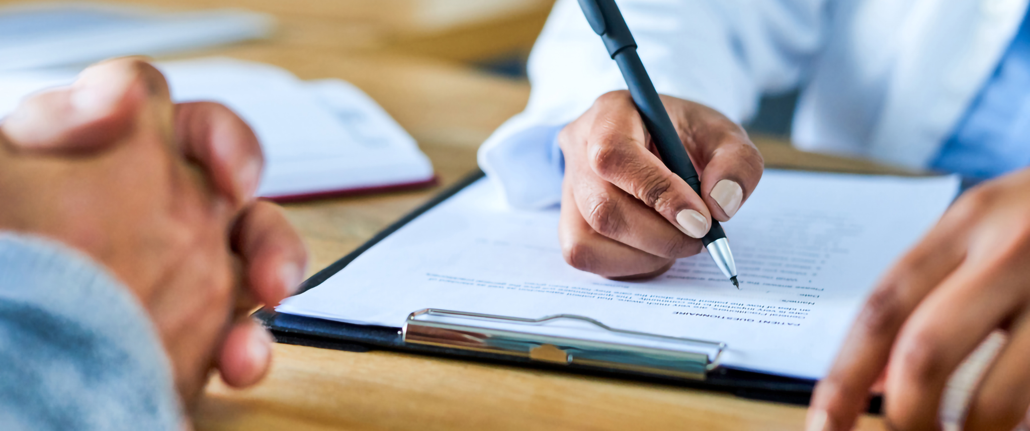 Doctor completing a form while seeing a patient in the office.