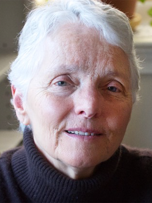 Marie, an older woman with short white hair, seen in close-up with a calm expression