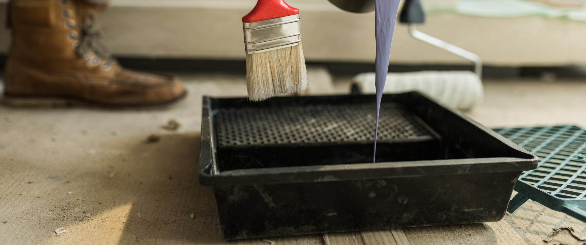 Man's arms pouring blue paint into paint trough