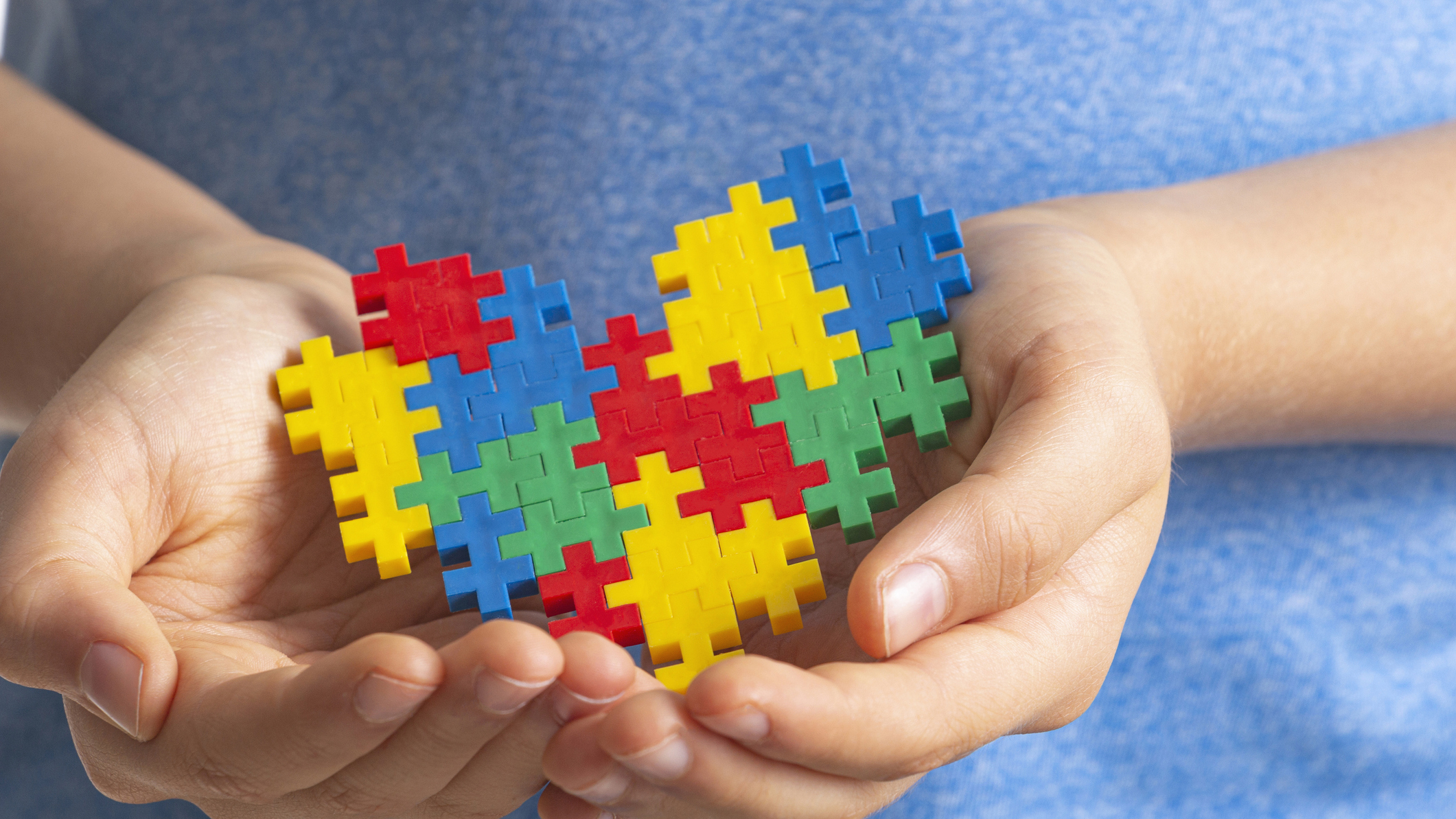 A child’s hands holding a colorful puzzle shaped like a heart