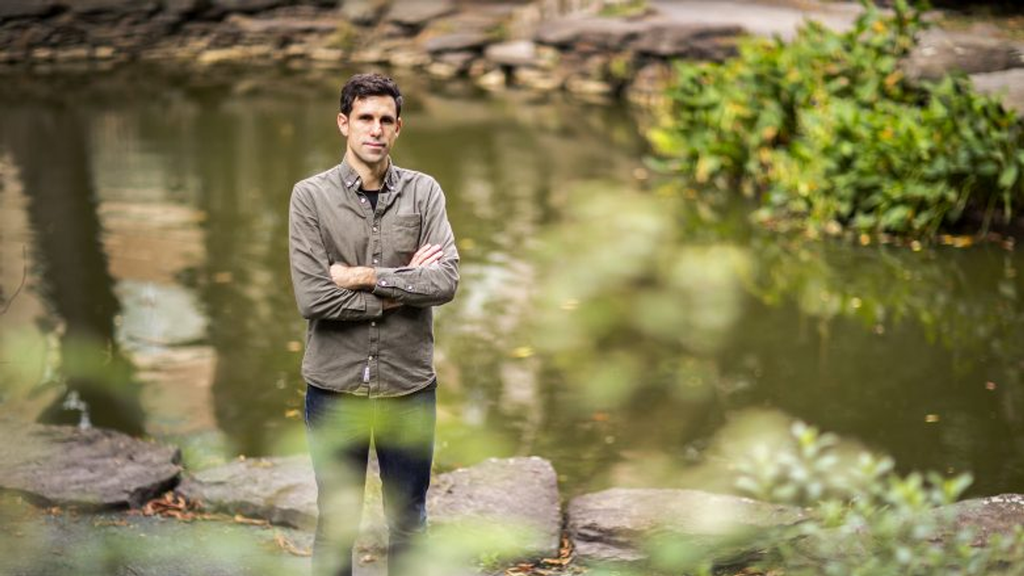 Portrait of Cesar de la Fuente standing in front of a pond