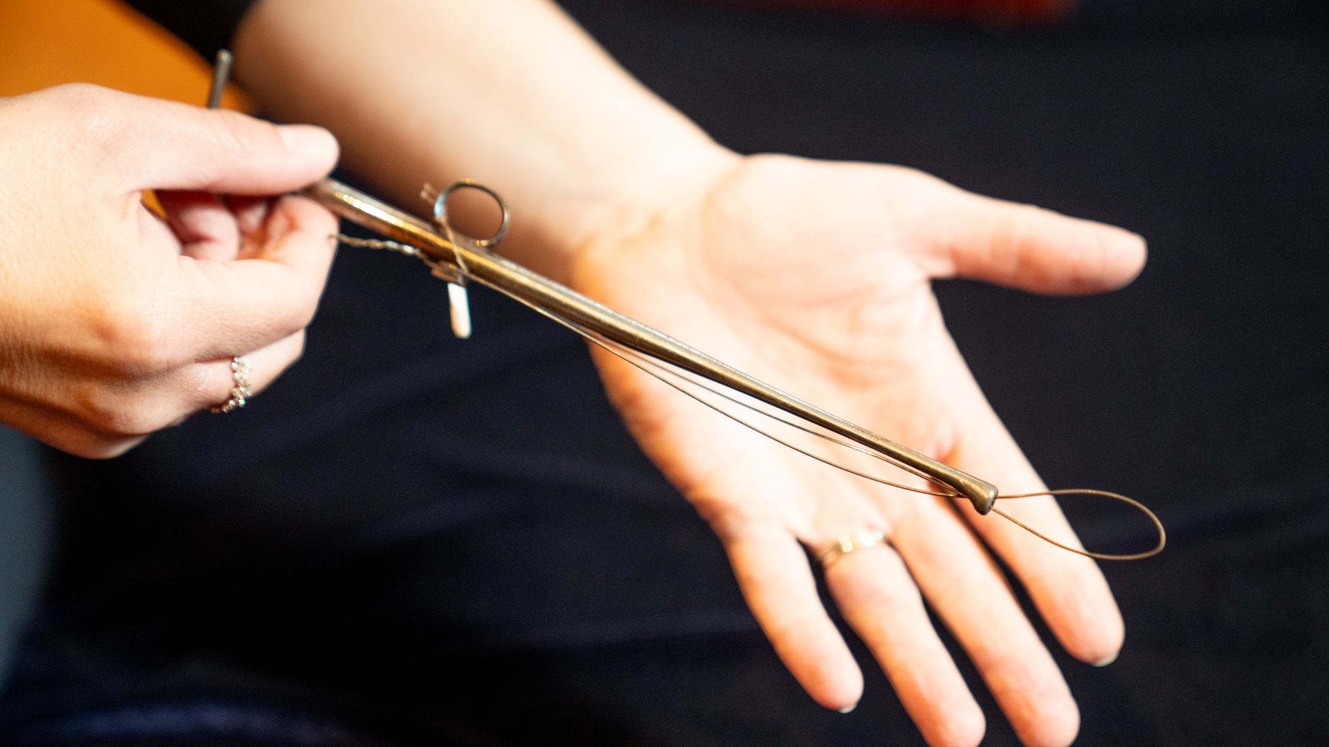 Hands holding the tonsil guillotine, an early surgical tool