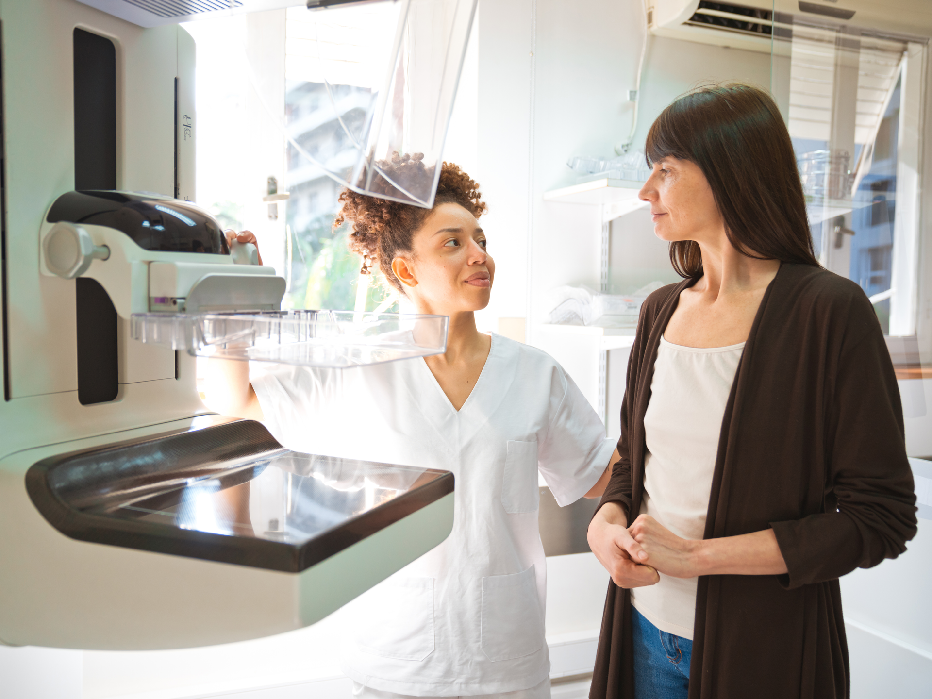 Female doctor talking to patient during Mammography test in examination room