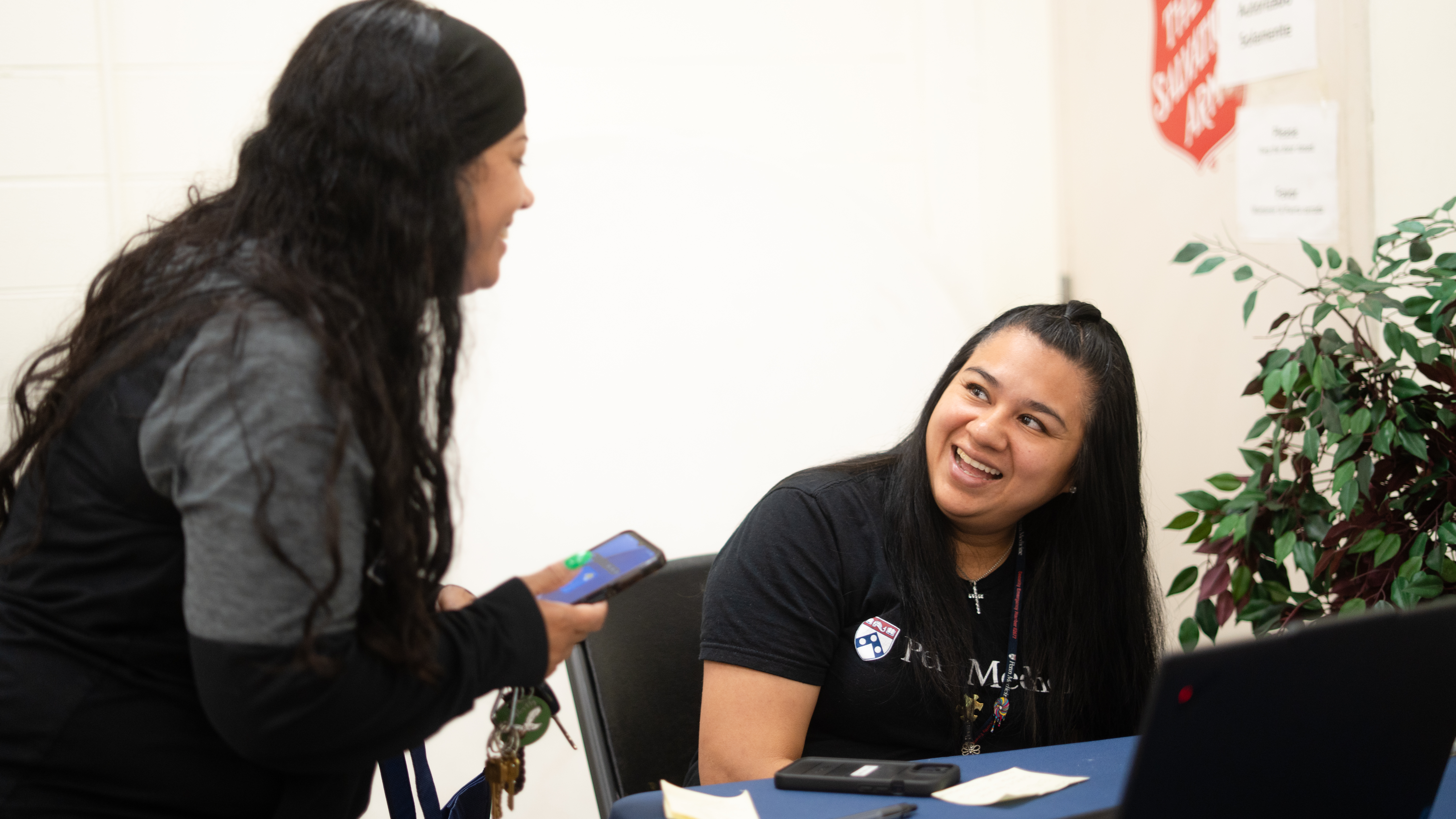 A Penn Medicine financial advocate smiles at a community member at an information table during an outreach event