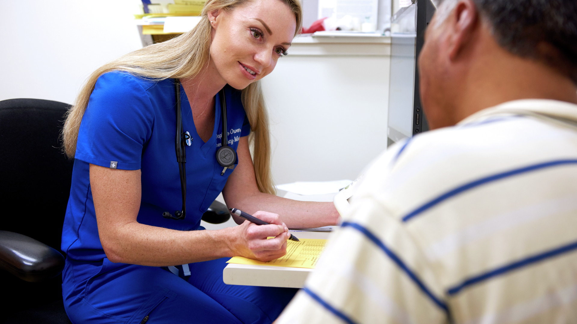 Daphne Owen, MD, has a warm expression as she takes notes, listening to a patient