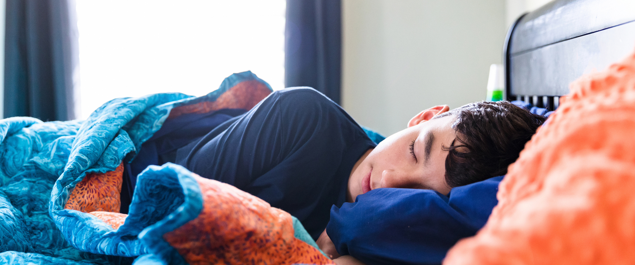 A teenage boy sleeping in a bed