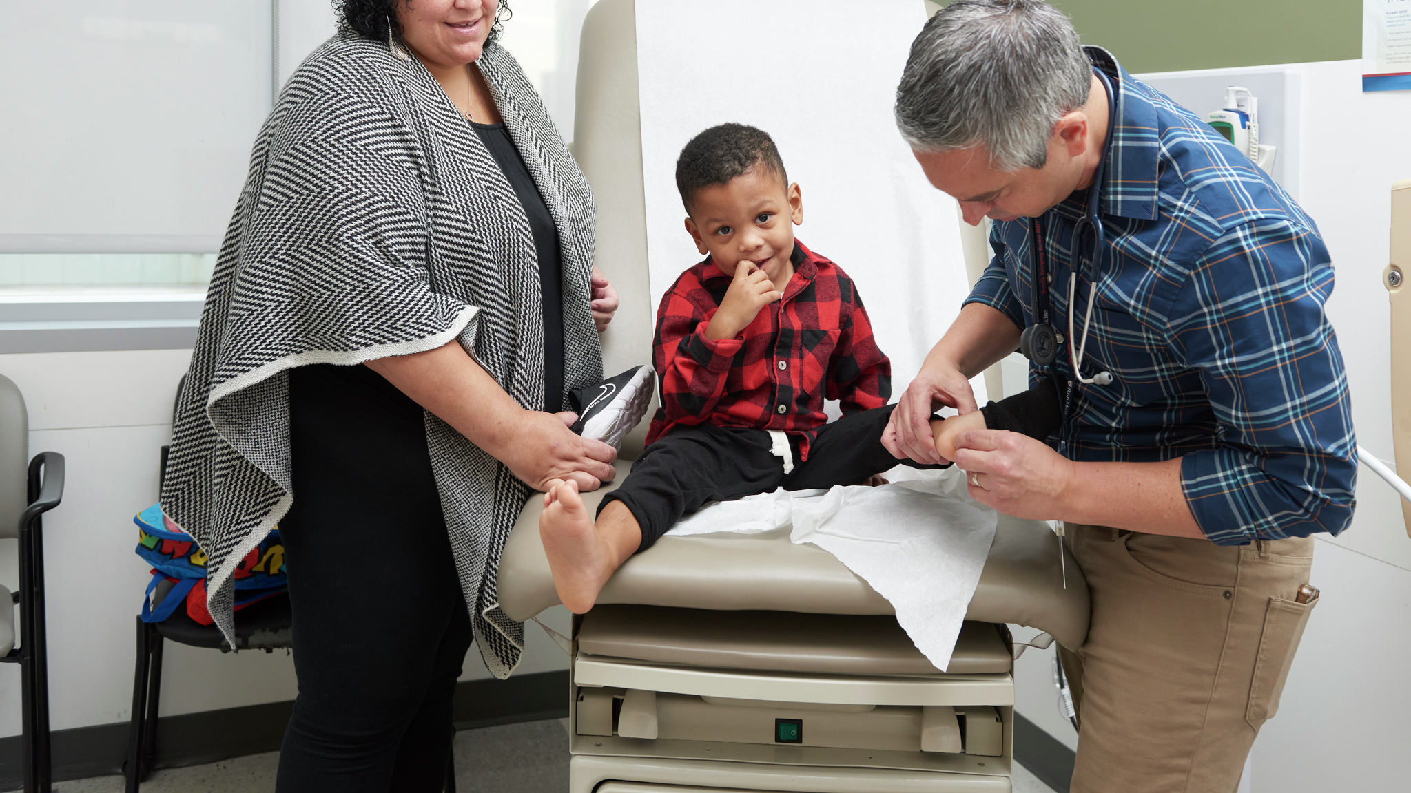 Nicole Miller watches as Mario DeMarco, MD, examines her 3-year-old son on an exam table