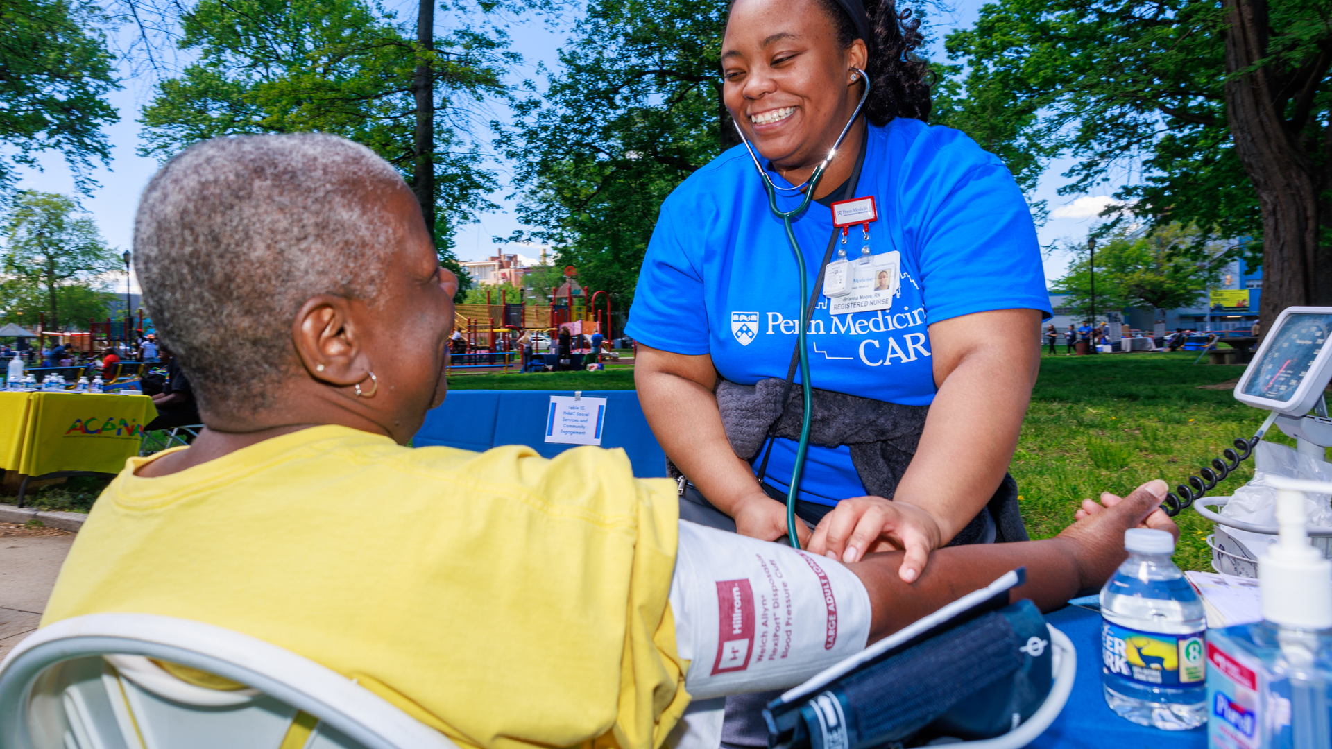 Brianna Moore, RN takes woman's blood pressure at a Penn Medicine Cares Nurses' Week event at Malcolm X park