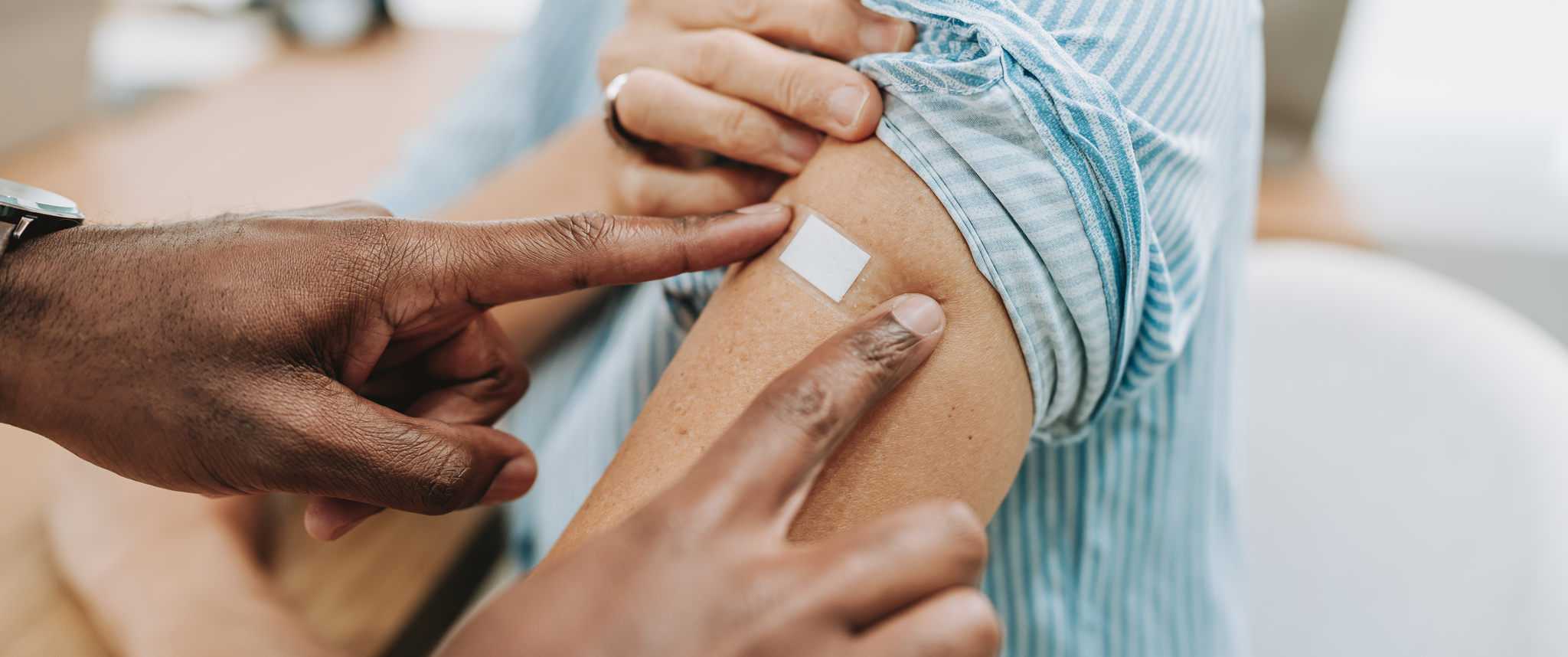 A doctor applies an adhesive bandage to older patient's arm