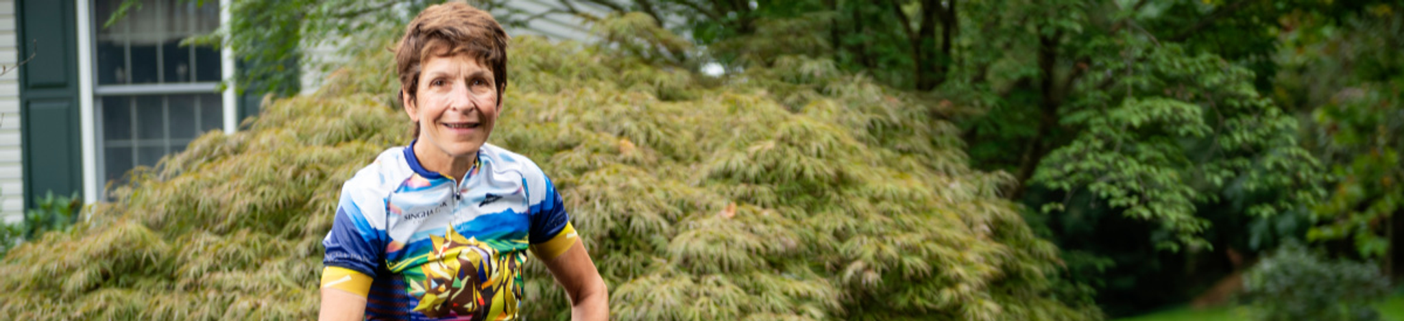 Woman standing with bicycle with trees in background