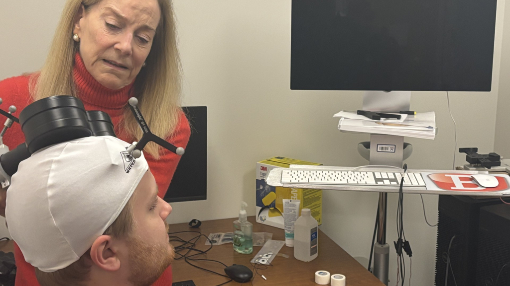 Yvette Sheline holds a device over the head of a man wearing a white cap