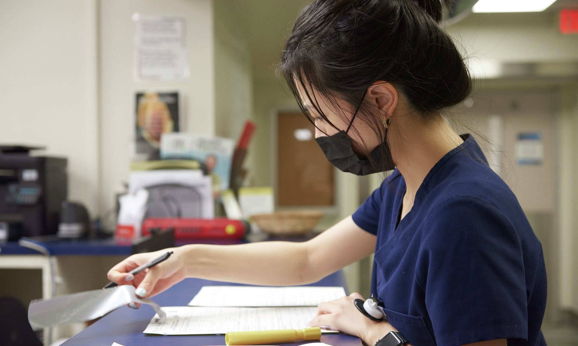 A nurse seen in profile reviews paper charts