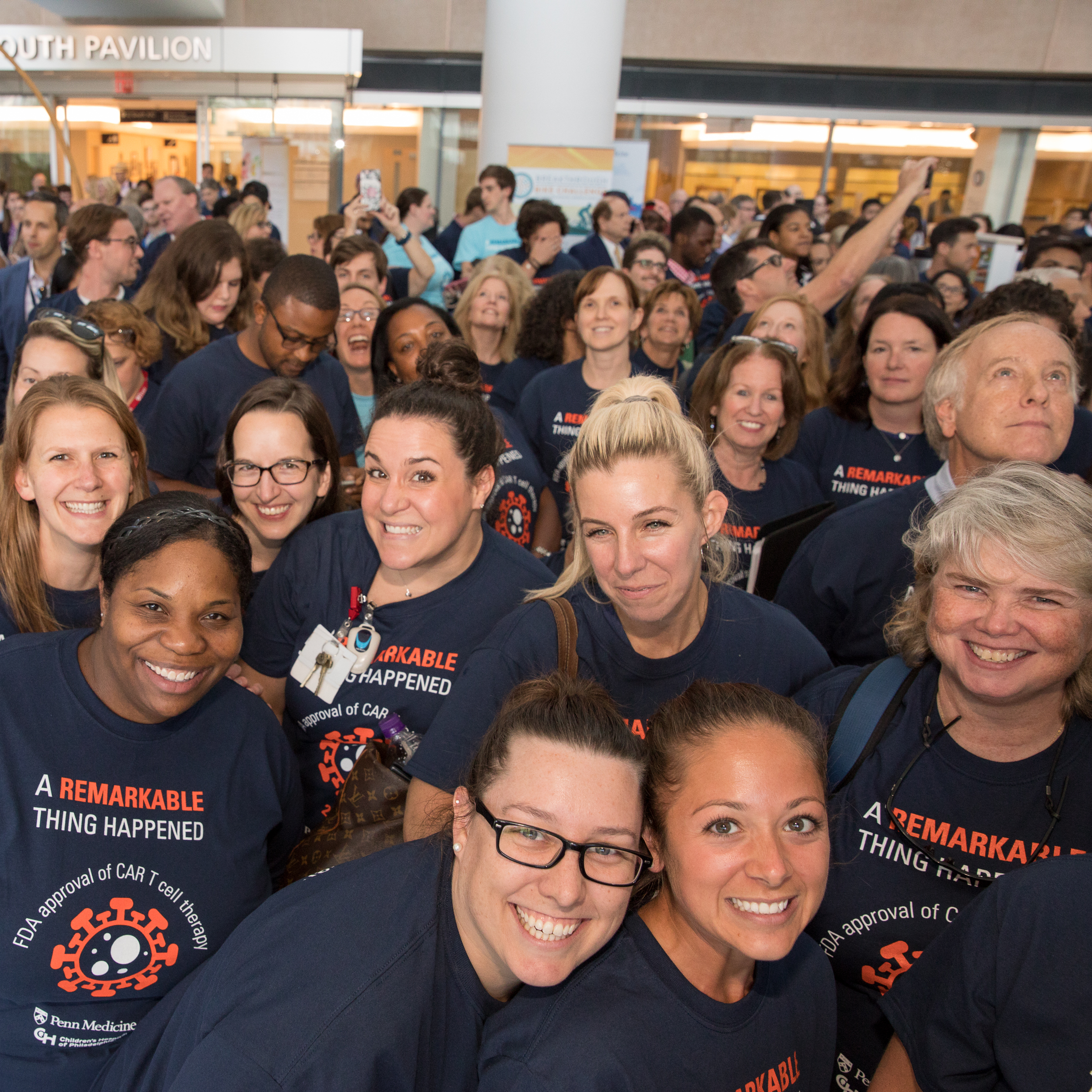 A group of attendees wearing "A remarkable thing happened" T-shirts smiles for a photo