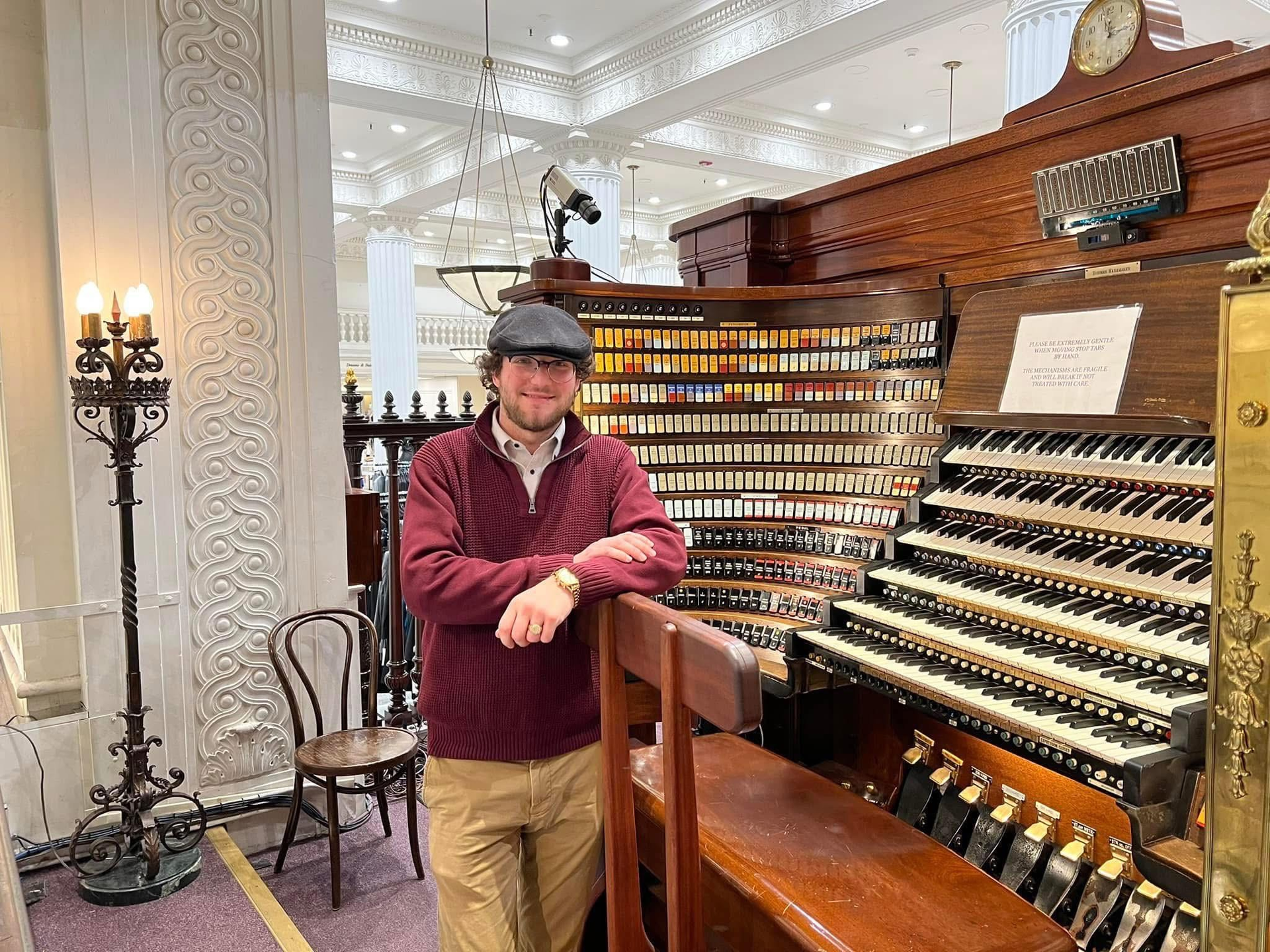 Tyler Schumacher standing beside an old-fashioned musical organ