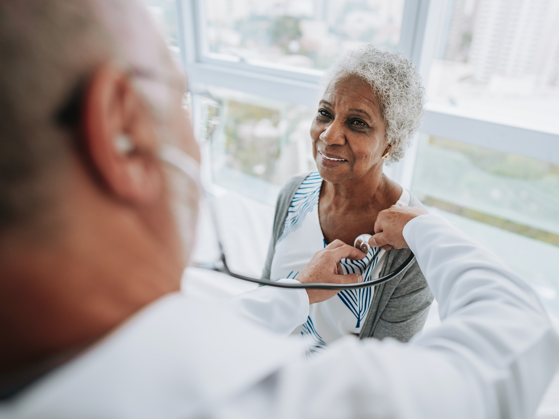 Doctor listening to an elderly woman patient's heartbeat