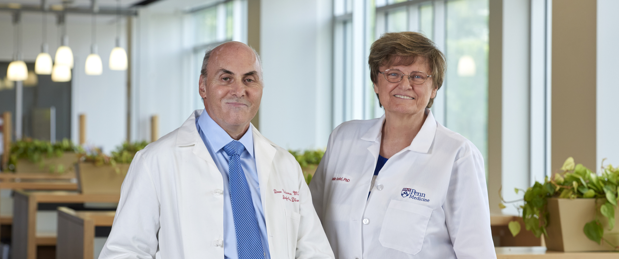 Drew Weissman and Katalin Kariko, smiling, wearing white coats