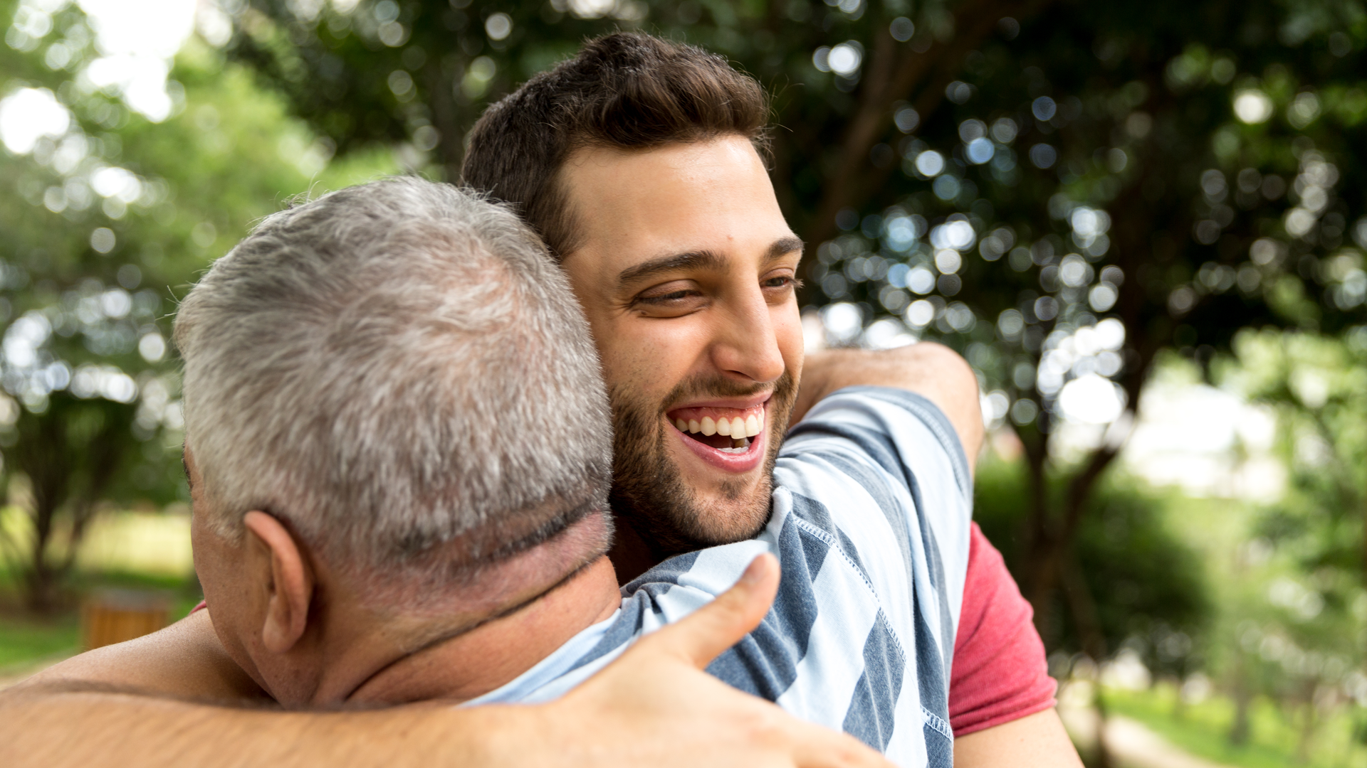 Adult son hugging his senior dad