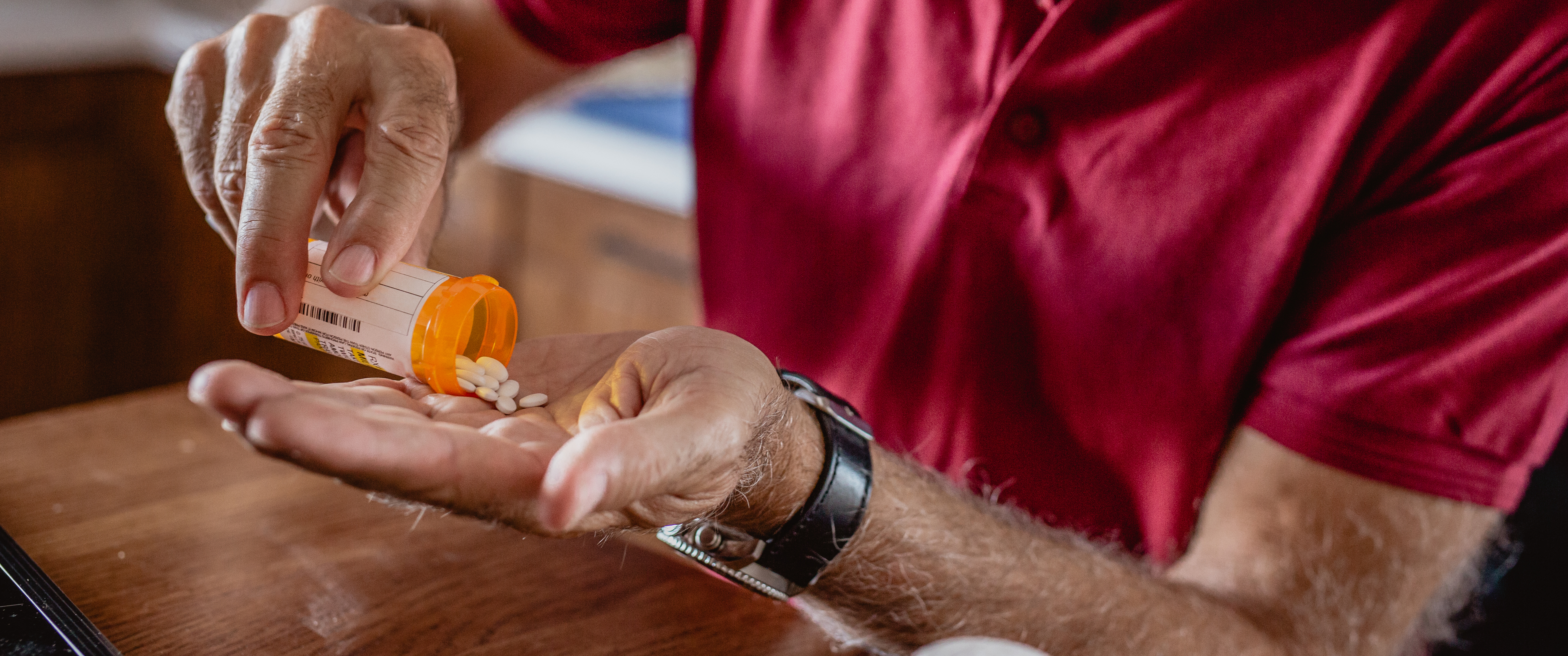 Man placing pills in his hand from bottle