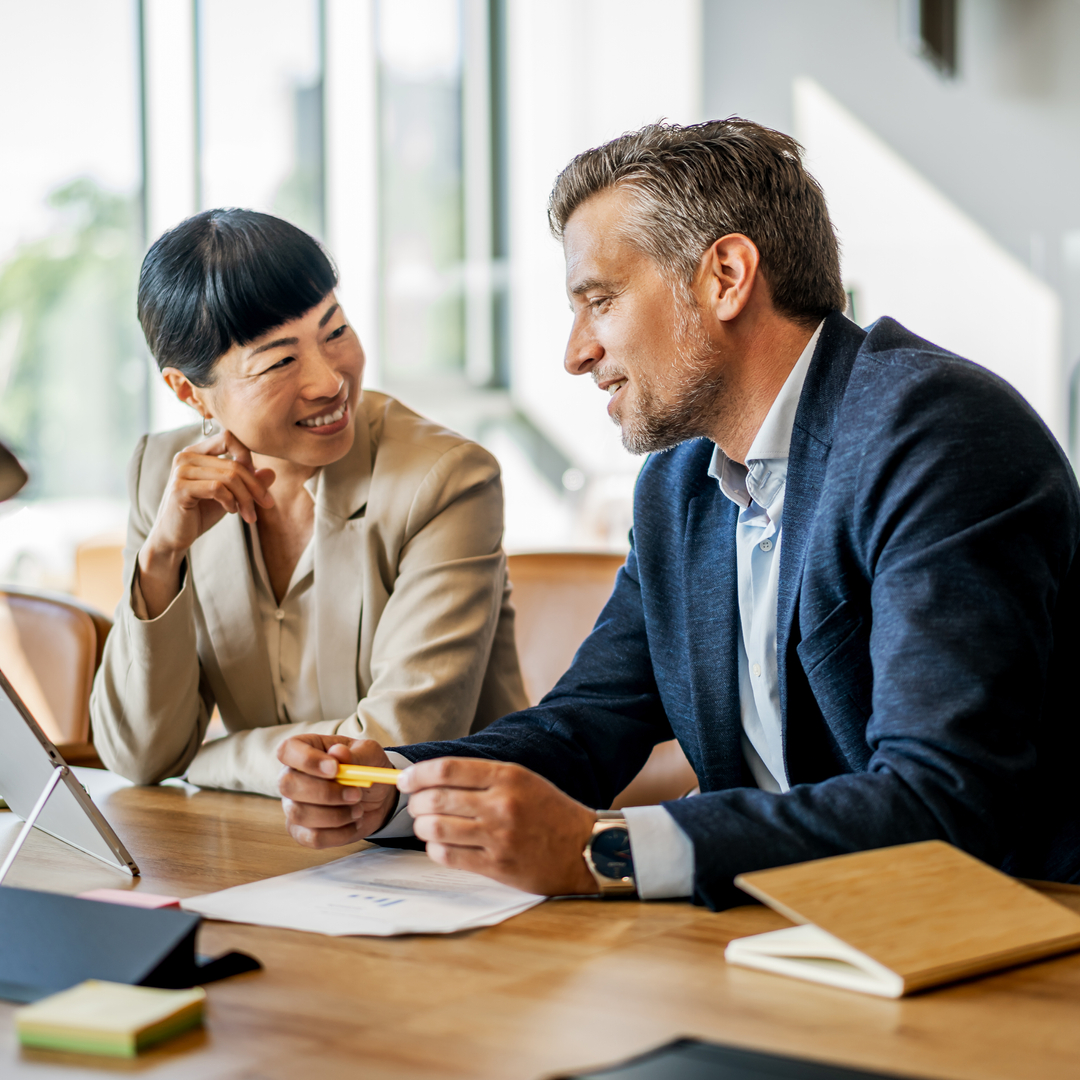 A financial employee and a patient are discussing financial support in a modern office, using a digital tablet and paperwork