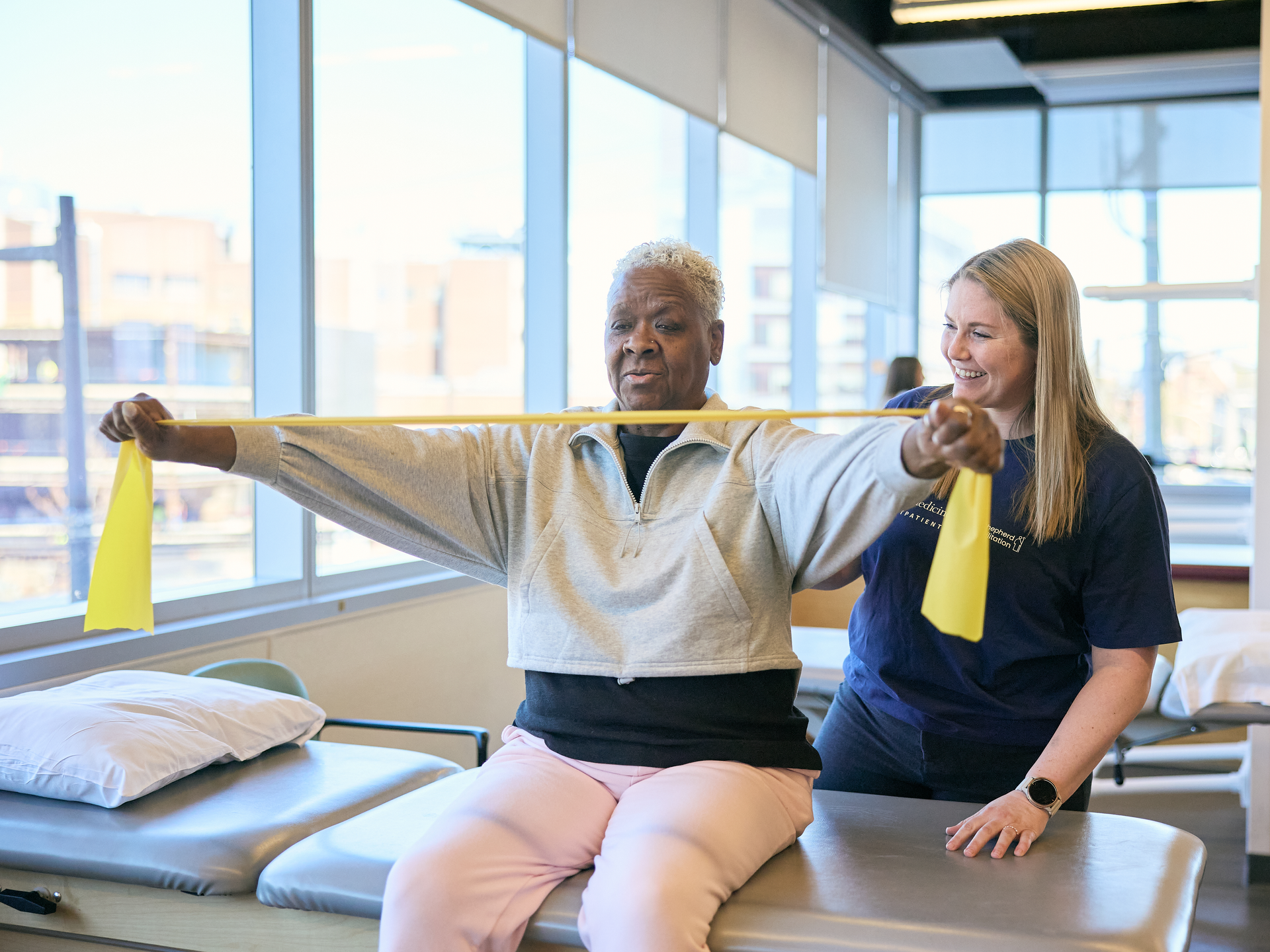 Patient uses resistance bands while physical therapist looks on at Good Shepard Penn Partners outpatient facility