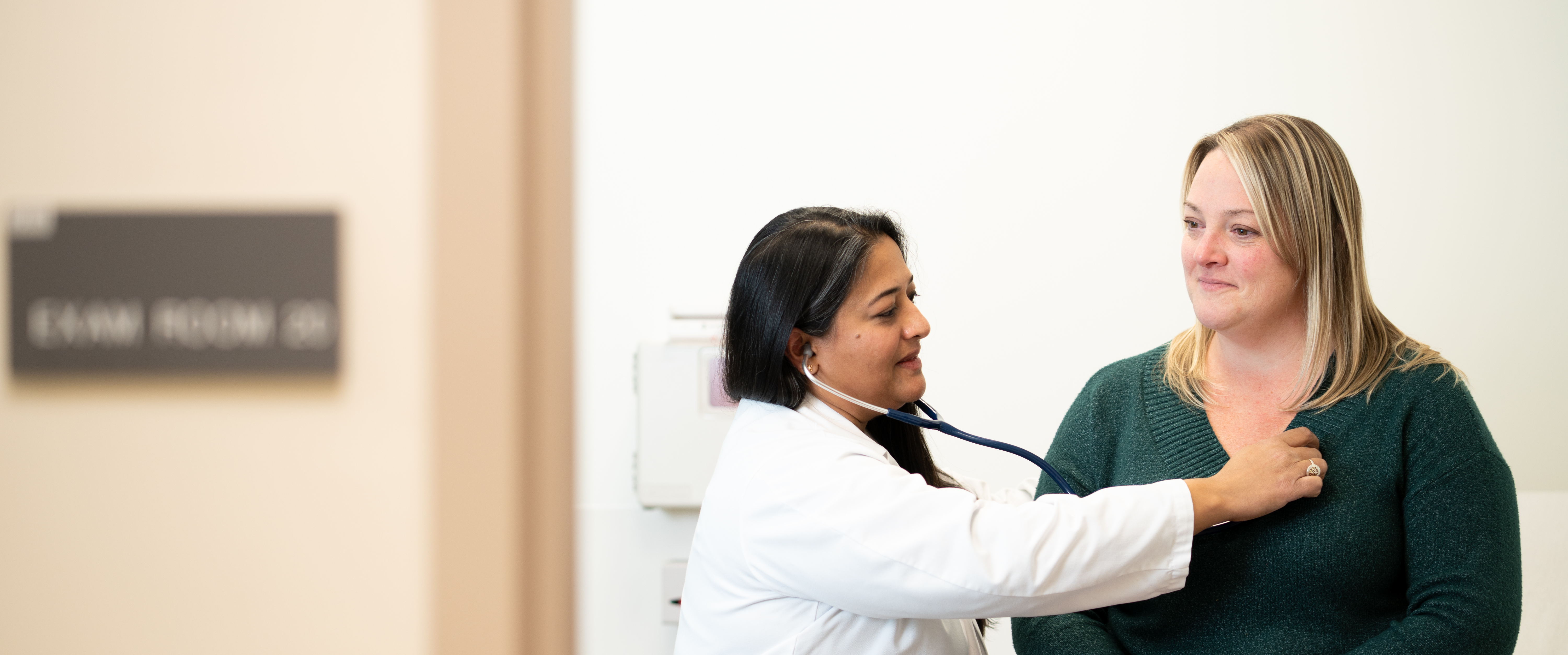 Aileen John puts a stethoscope to a patient’s chest.
