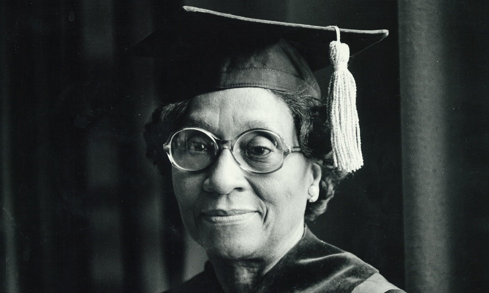 A black and white photo of Helen O. Dickens wearing graduation regalia