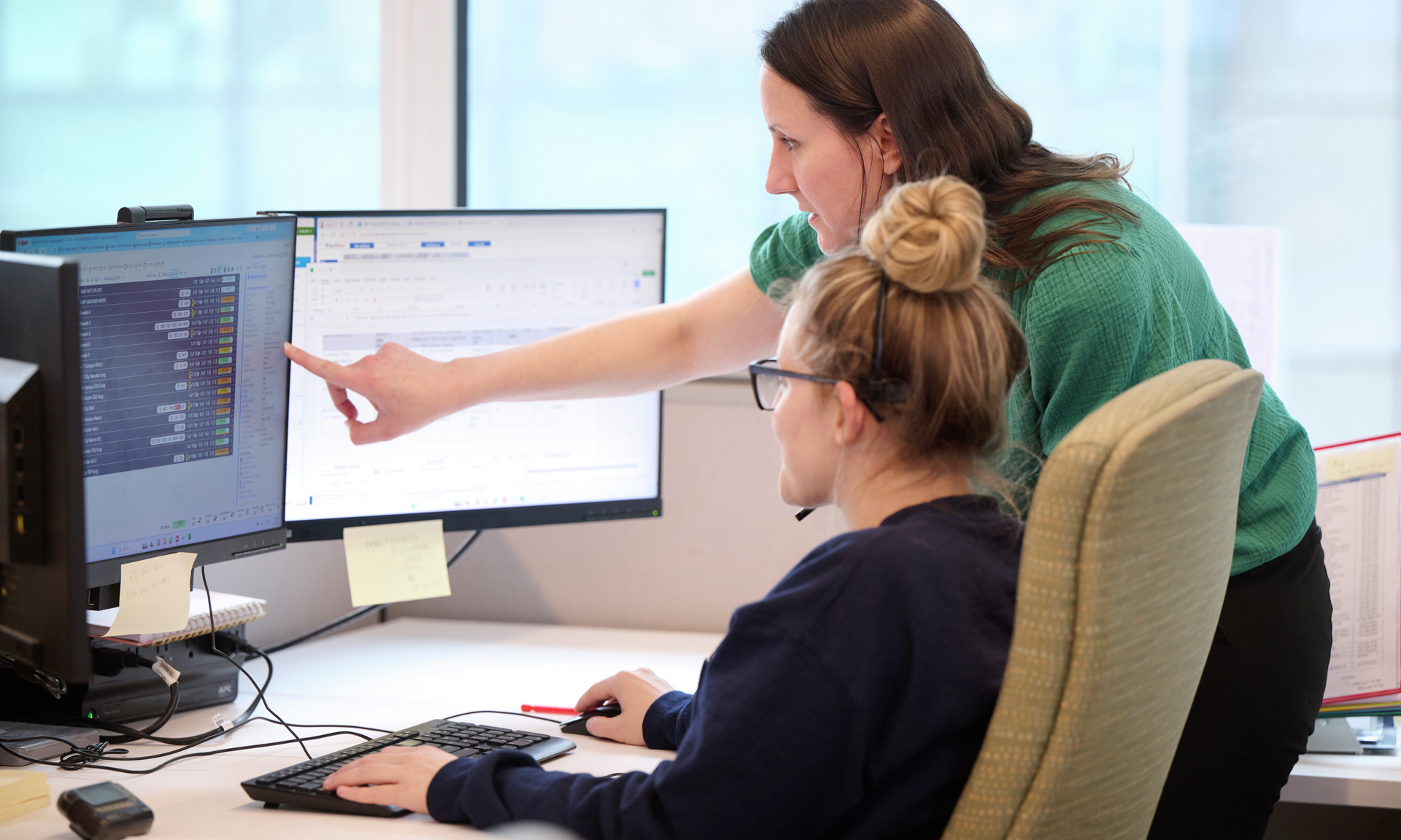 Amanda Whartenby points at a screen while a capacity management nurse looks at data