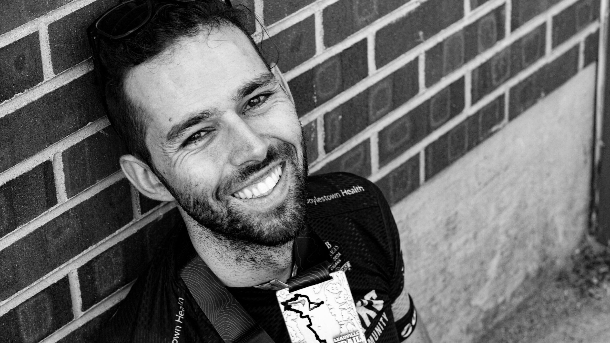 Chris Baccash sits against a brick wall after finishing a bike race
