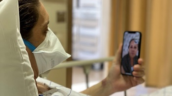 Donald, wearing a mask and sitting in a hospital bed, talks on FaceTime