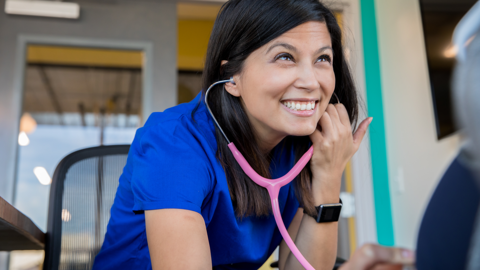 Female nurse using a stethoscope while meeting with pregnant patient