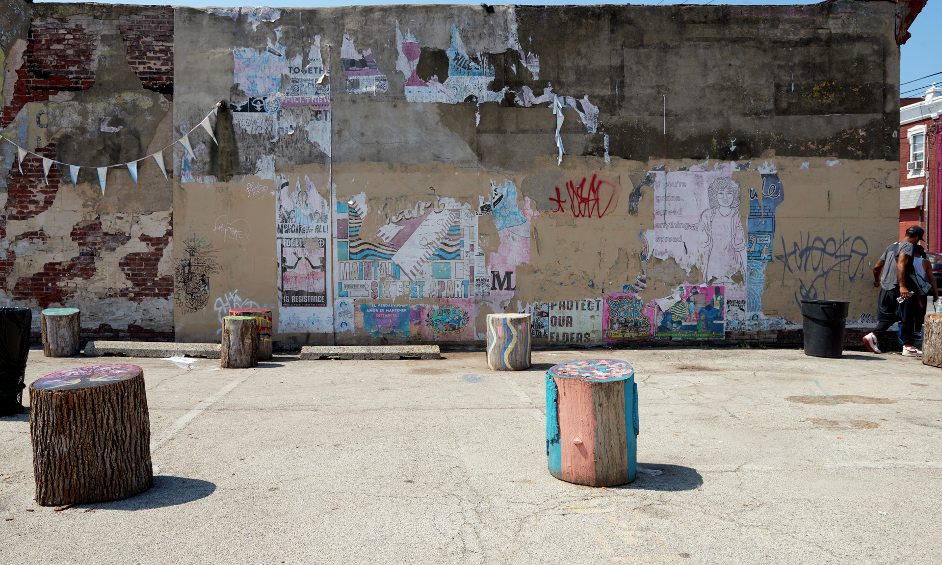 The Love Lot, a parking lot with painted tree stumps and colorful graffiti and peeling posters on a wall